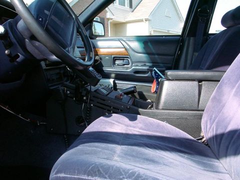 1999 Ford Crown Victoria - The interior of a 1999 Ford Crown Victoria police car is visible, the dashboard, steering wheel, and center console equipment.