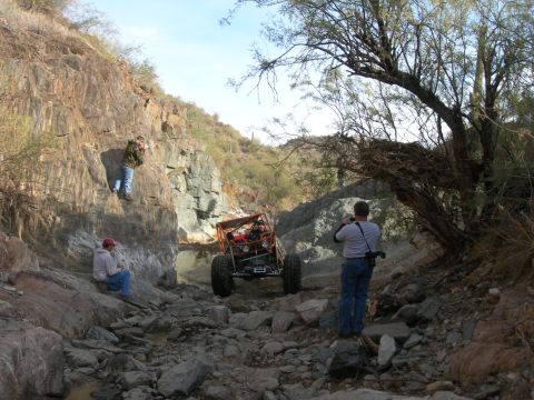 1974 Ford F-250 - Off-road buggy driving through a rocky canyon with spectators.
