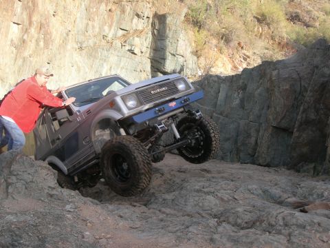 1974 Ford F-250 - A man helps push a Suzuki Samurai navigating a difficult rocky trail.