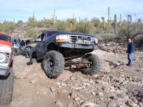 1986 Toyota Hilux - Modified Ford F-150 truck navigates challenging rocky terrain with other vehicles present.