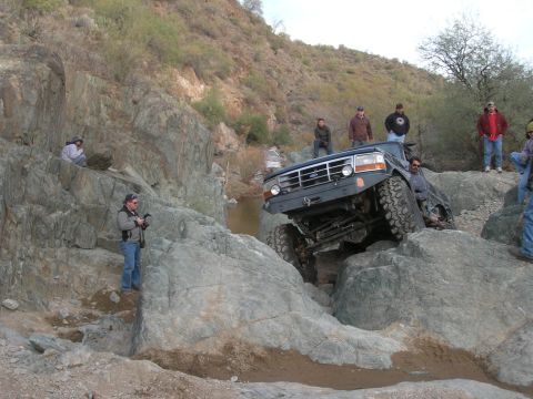 1974 Ford F-250 - A modified truck is navigating a difficult rocky trail with spectators present.