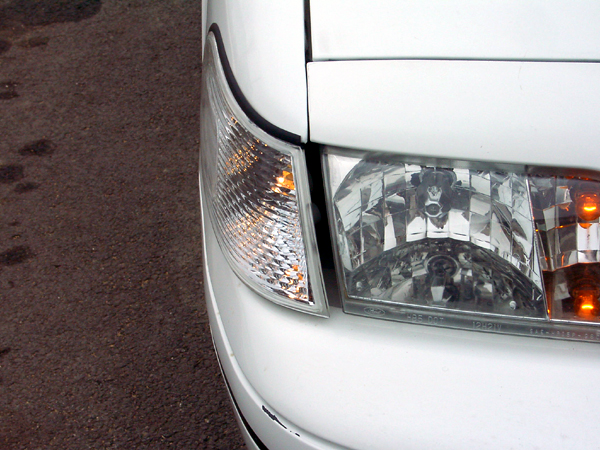 White car front corner, clear turn signal and headlight. 1999 Ford Crown Victoria