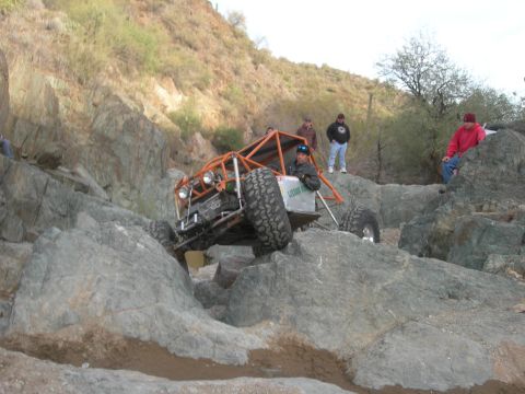 1974 Ford F-250 - An off-road buggy tackles a challenging rocky obstacle during an event.
