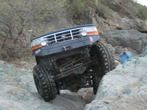 1974 Ford F-250 - A blue Ford truck, likely from the early 1990s, tackles a challenging rocky off-road course.