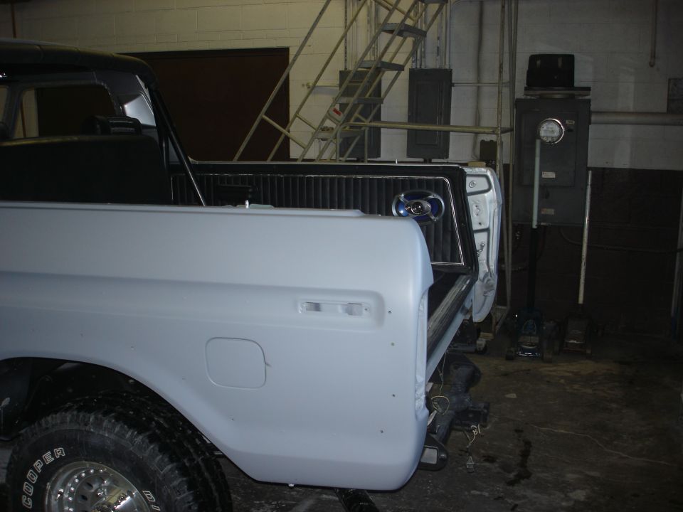1978 Ford Bronco rear quarter panel, tailgate area, and bed interior, unpainted. Visible Cooper tire