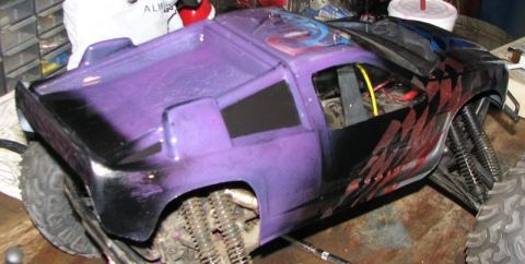 1999 Ford F-150 - A custom-painted remote control monster truck sits on a workbench, showing off its unique purple and black design.