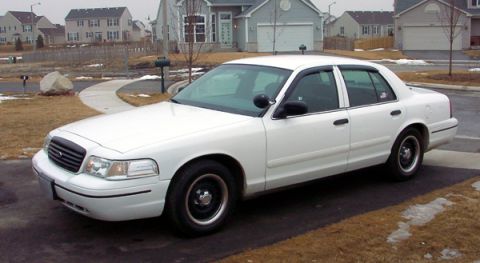 1999 Ford Crown Victoria - This white sedan is parked in a suburban driveway during a cloudy day.