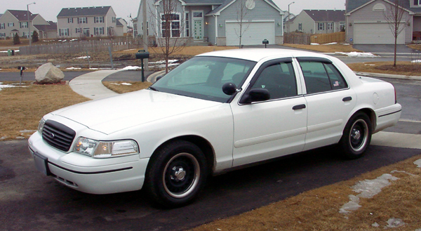 White sedan parked in a driveway with houses in the background
