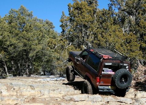 1986 Ford Bronco II - A 1986 Ford Bronco II navigates a rocky trail with a clear blue sky overhead.