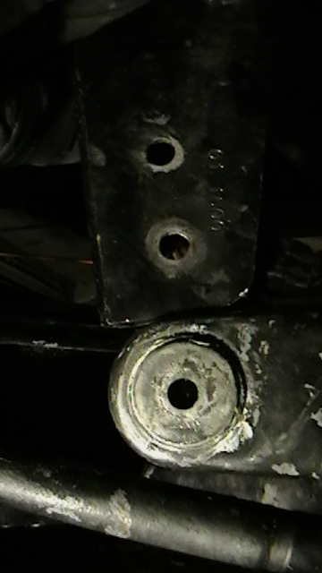 1995 Ford Bronco - A close-up view of a vehicle's suspension part, possibly an axle pivot bracket, showing wear and bolt holes.