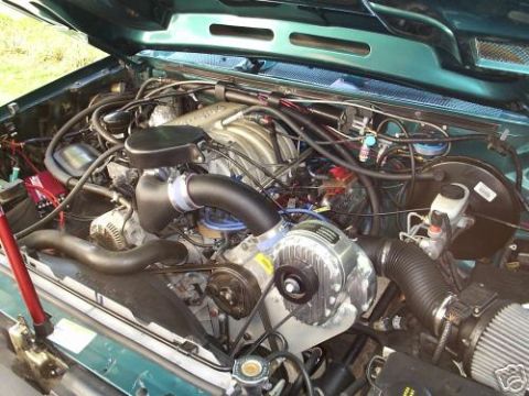 1992 Ford F-150 - The engine bay of a 1992 Ford F-150 features a prominent supercharger and custom intake system.
