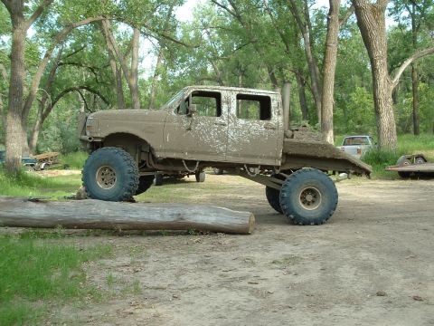 1992 Ford F-350 - This heavily modified truck is covered in mud, suggesting it has been off-roading. A log is positioned under its front tire.