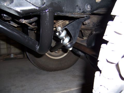 1980 Ford Bronco - Close-up of the undercarriage, showing suspension components and a tire, with black roll cage tubing visible.