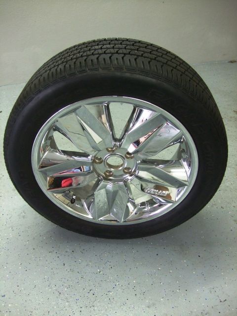 1987 Ford Bronco - A single chrome wheel and tire assembly is shown, resting on a speckled garage floor.