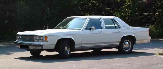 White full-size four-door sedan parked, front three-quarter view