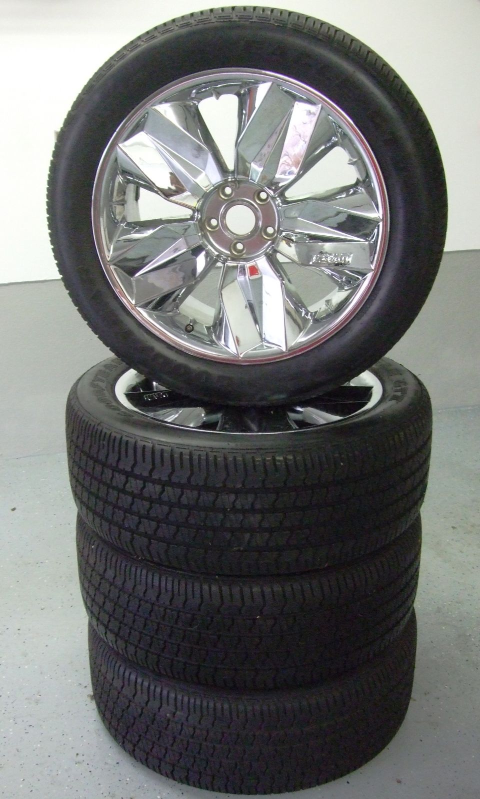 Stack of four tires with a chrome rim wheel on top