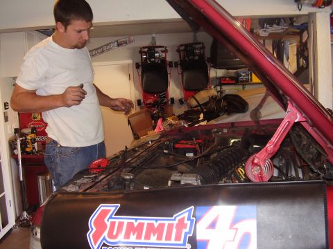 1994 Ford Bronco - A man is working on the engine of a red vehicle in a garage, with a Summit Racing fender cover in place.