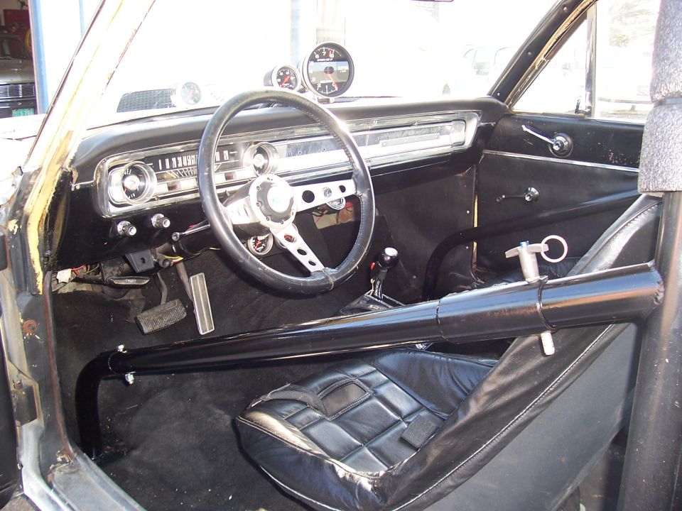 Race-modified Ford Falcon interior with roll cage, aftermarket gauges, and bucket seat
