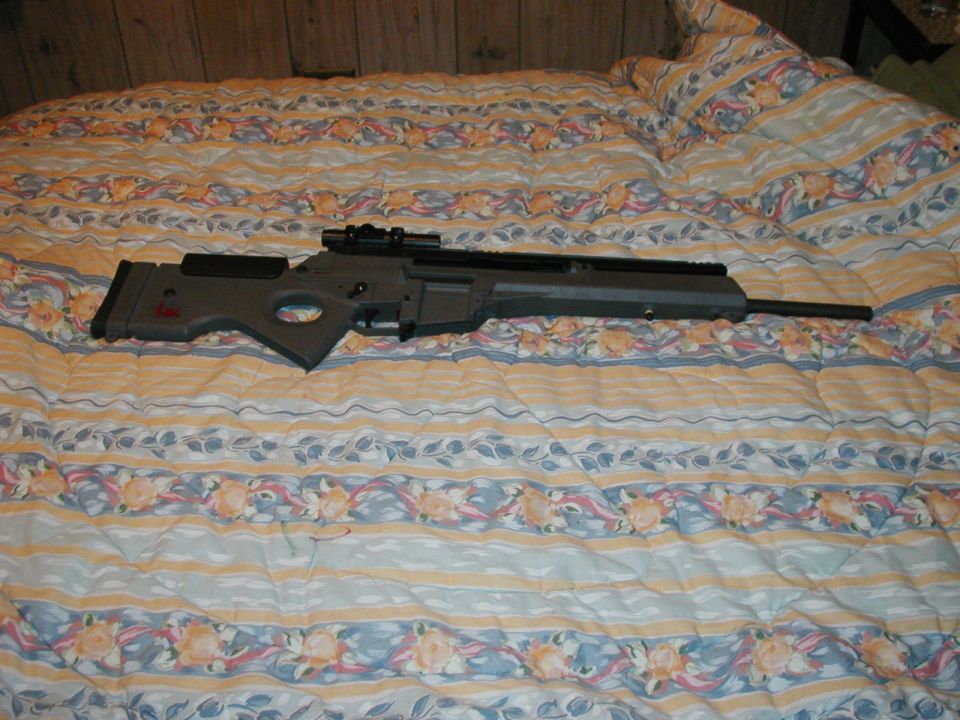 Sniper rifle with scope on a patterned comforter