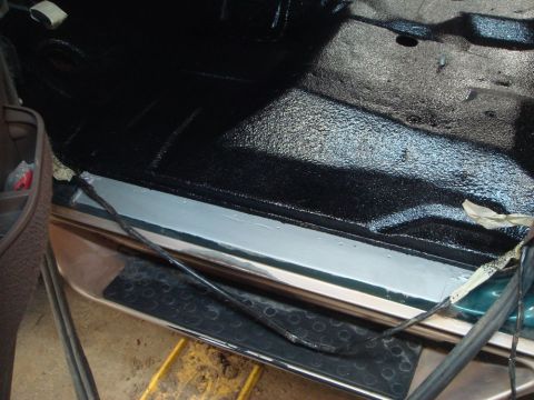 1996 Ford Bronco - The interior floor and door sill area shows a black textured coating and some exposed wiring, suggesting recent work or repair.