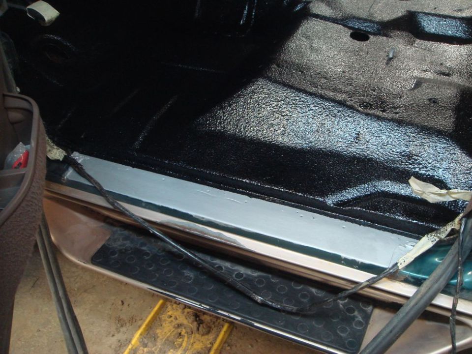 Interior floor and door sill with black textured coating and exposed wiring