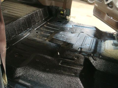 1996 Ford Bronco - The interior floor of a vehicle has been treated with a textured black coating for protection.