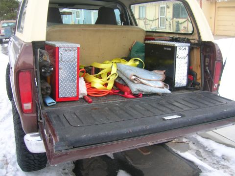 1979 Ford Bronco - Rear view of a maroon and white SUV with the tailgate dropped, showing the cargo area packed with two diamond-plate tool boxes (one red-sid…