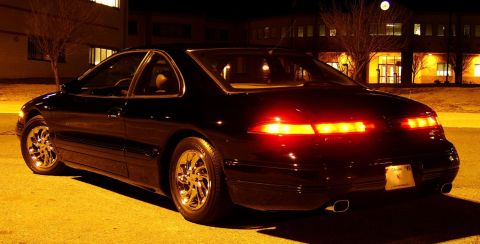 1996 Mercury Grand Marquis - A black coupe is parked at night, its taillights illuminated against the dark background.