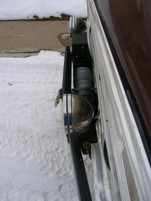 1979 Ford Bronco - A winch and bumper assembly is visible on the front of a vehicle covered in snow.