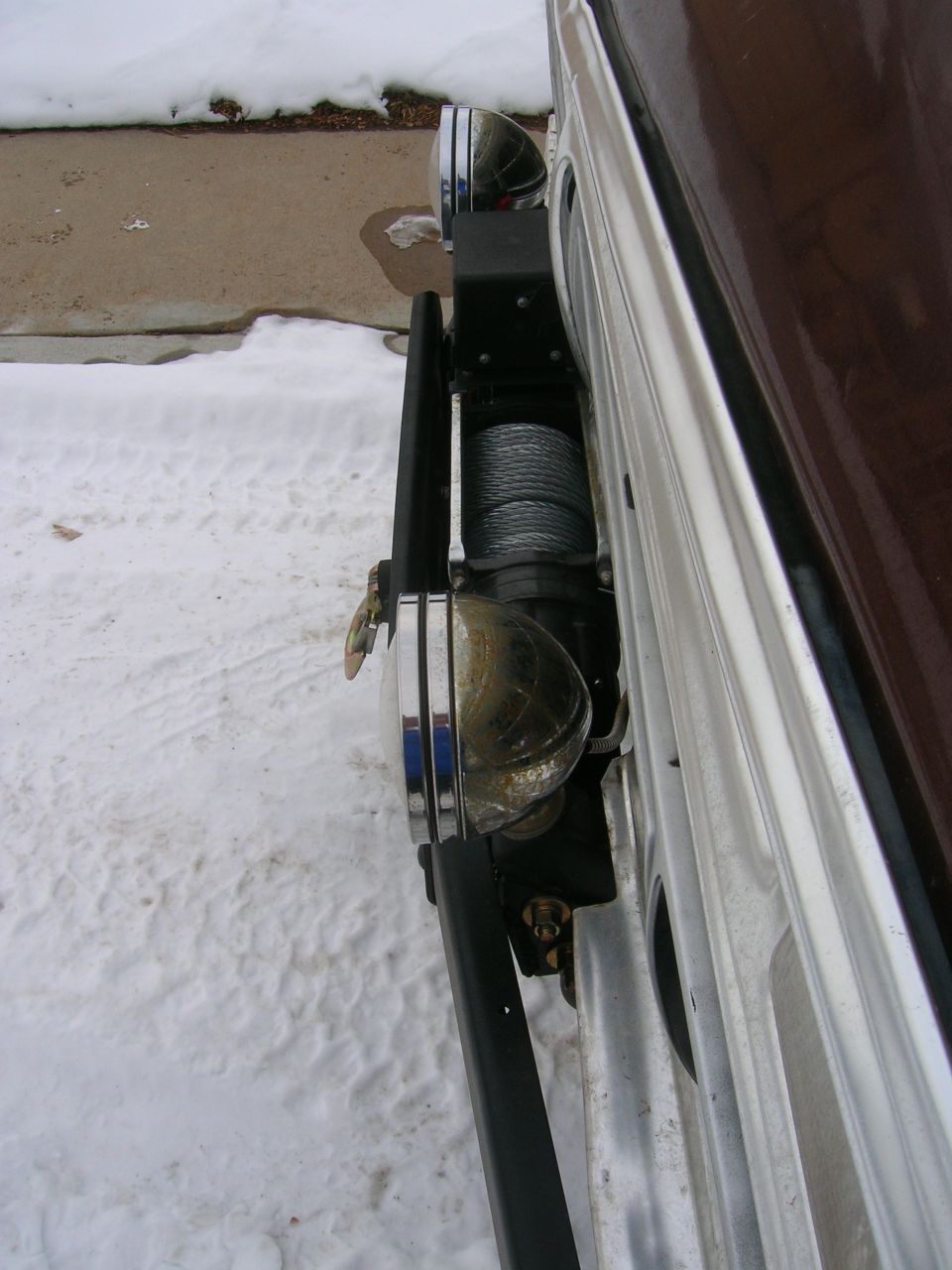 Winch and chrome bumper with auxiliary lights on a vehicle in the snow