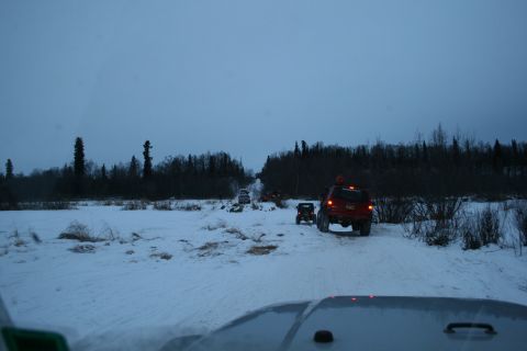 2003 Jeep TJ - Off-road vehicles navigate a snowy path in a wooded landscape under an overcast sky.