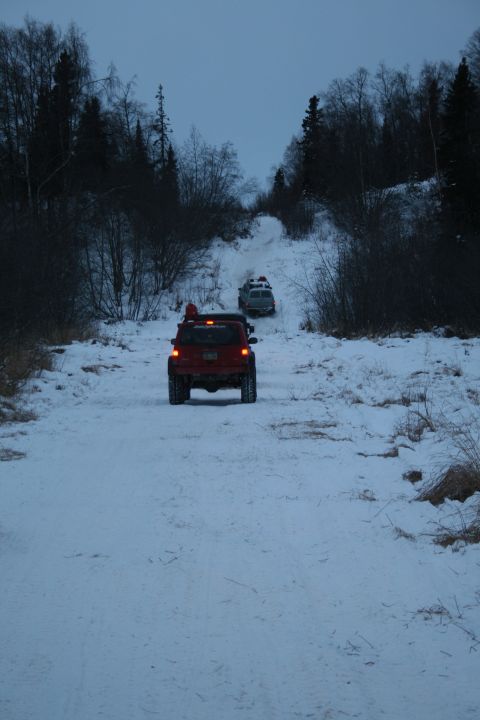 2003 Jeep TJ - Two SUVs navigate a snow-covered trail through a wooded area.