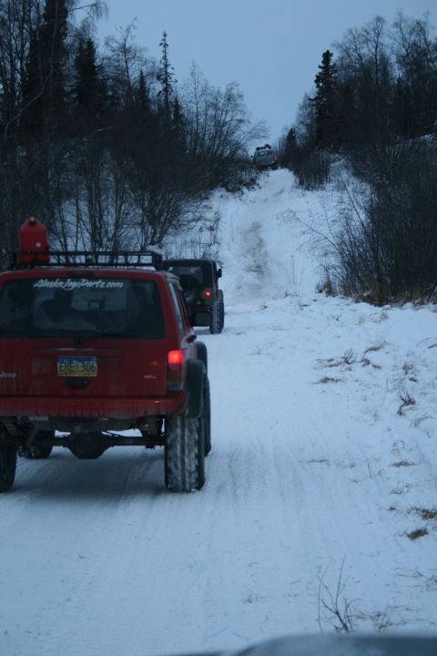 2003 Jeep TJ - Several Jeeps navigate a snowy trail in a wooded area.