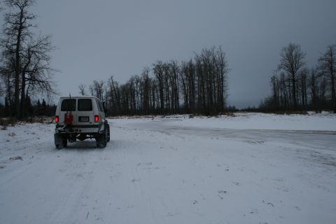 2003 Jeep TJ - A white van travels through a snowy landscape with bare trees lining the horizon.