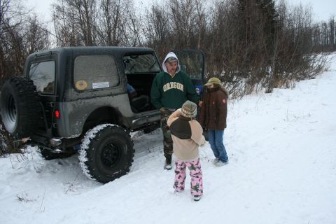 2003 Jeep TJ - A group of people stand near a gray Jeep Wrangler parked in a snowy landscape.
