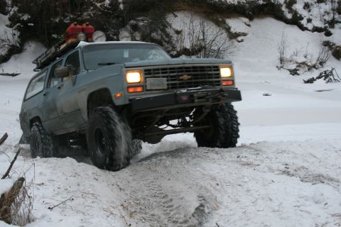 2003 Jeep TJ - Modified Chevrolet K5 Blazer navigating a snowy terrain with auxiliary fuel cans on the roof.