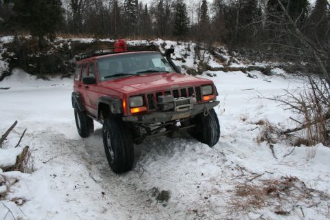 2003 Jeep TJ - Red 2003 Jeep TJ navigates a snowy trail with a winch and roof rack.