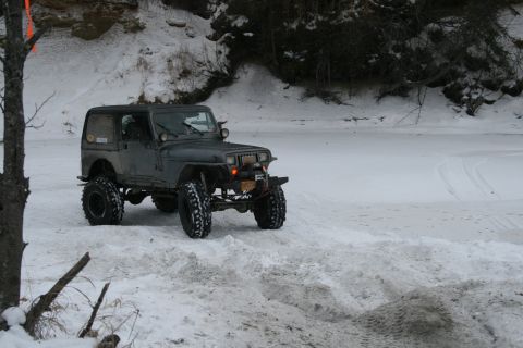 2003 Jeep TJ - A modified Jeep Wrangler sits on a snowy bank next to a frozen river.