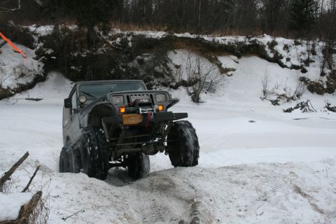 2003 Jeep TJ - A Jeep Wrangler navigates a snow-covered trail near a frozen body of water.