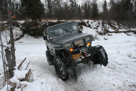 2003 Jeep TJ - A Jeep Wrangler YJ navigates a snowy terrain with a winch mounted on its front bumper.