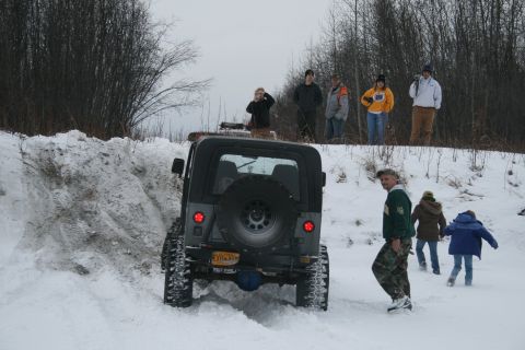 2003 Jeep TJ - A Jeep TJ navigates a snowy path with onlookers observing from a snow-covered embankment.