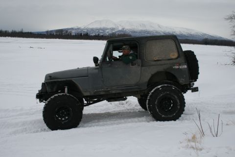 2003 Jeep TJ - Driver navigates a 2003 Jeep TJ through a snow-covered landscape with mountains visible.