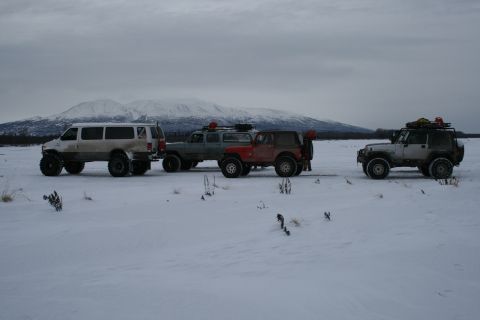 2003 Jeep TJ - Several modified off-road vehicles are parked in a snowy field with mountains in the distance.