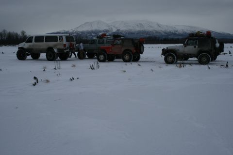 2003 Jeep TJ - A convoy of off-road vehicles, including a van and several Jeeps, are stopped in a snow-covered field.