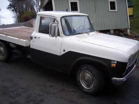 1988 Mazda RX-7 - This flatbed pickup truck features a two-tone paint scheme and a wooden bed, parked in front of a residential building.