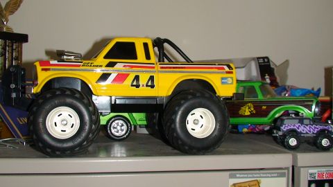1979 Ford Bronco - Multiple toy trucks are displayed on a shelf, including a yellow monster truck.
