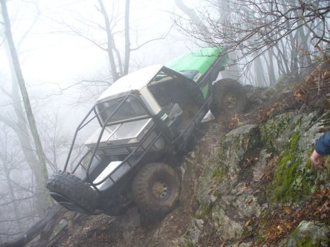 1978 Ford Bronco - A heavily modified off-road vehicle navigates a challenging rocky incline amidst foggy conditions.