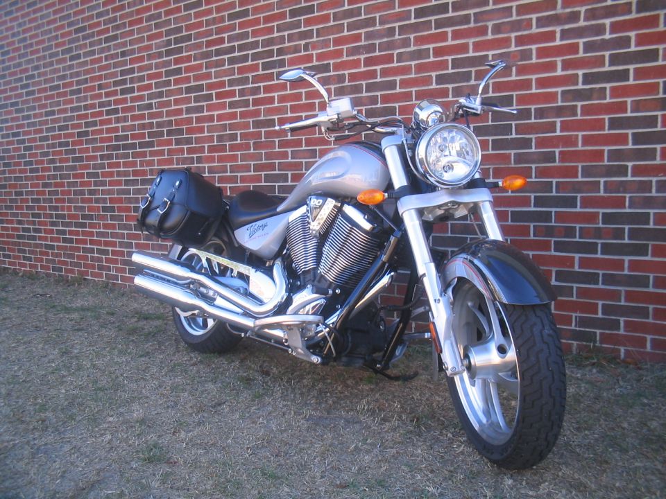 Silver 2006 Victory Kingpin motorcycle with black saddlebags parked in front of a brick wall