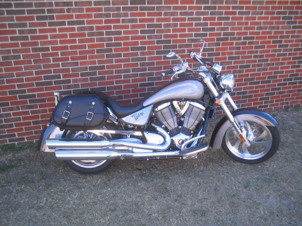 Silver Victory cruiser motorcycle, left side, parked by brick wall