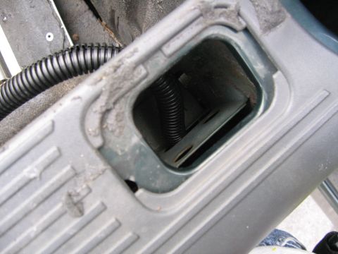 2001 Ford F-150 - A view inside a vehicle showing a gray plastic trim piece with a black wire conduit visible through an opening.